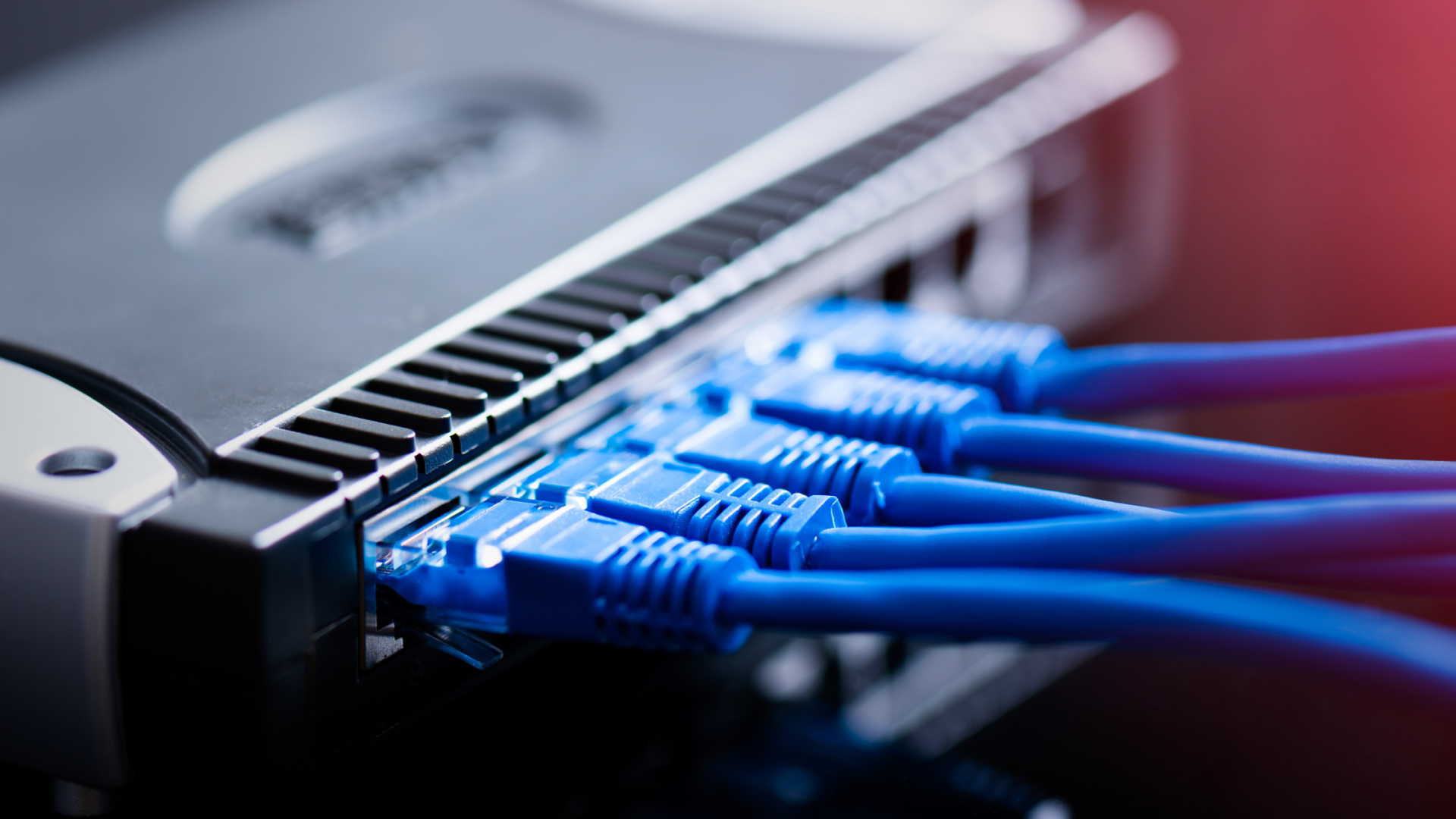 MikroTik RouterOS Zero-Days Under Attack - Intrix Cyber Security | Pen Testing, AI, GRC & Managed Security Close-up of a network switch with blue Ethernet cables plugged into the ports